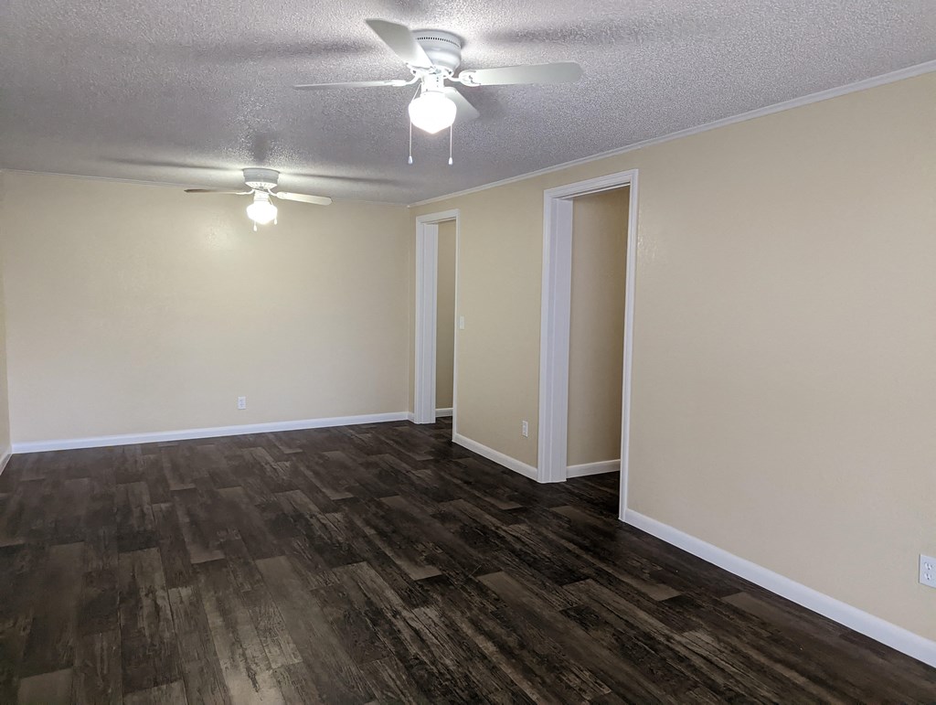 an empty living room with wood flooring and a ceiling fan