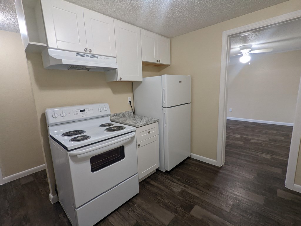 an empty kitchen with white appliances and a refrigerator