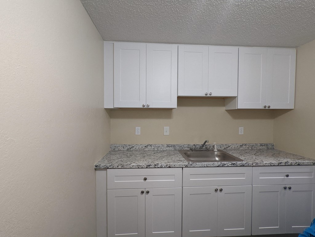 a kitchen with white cabinets and granite counter tops and a sink