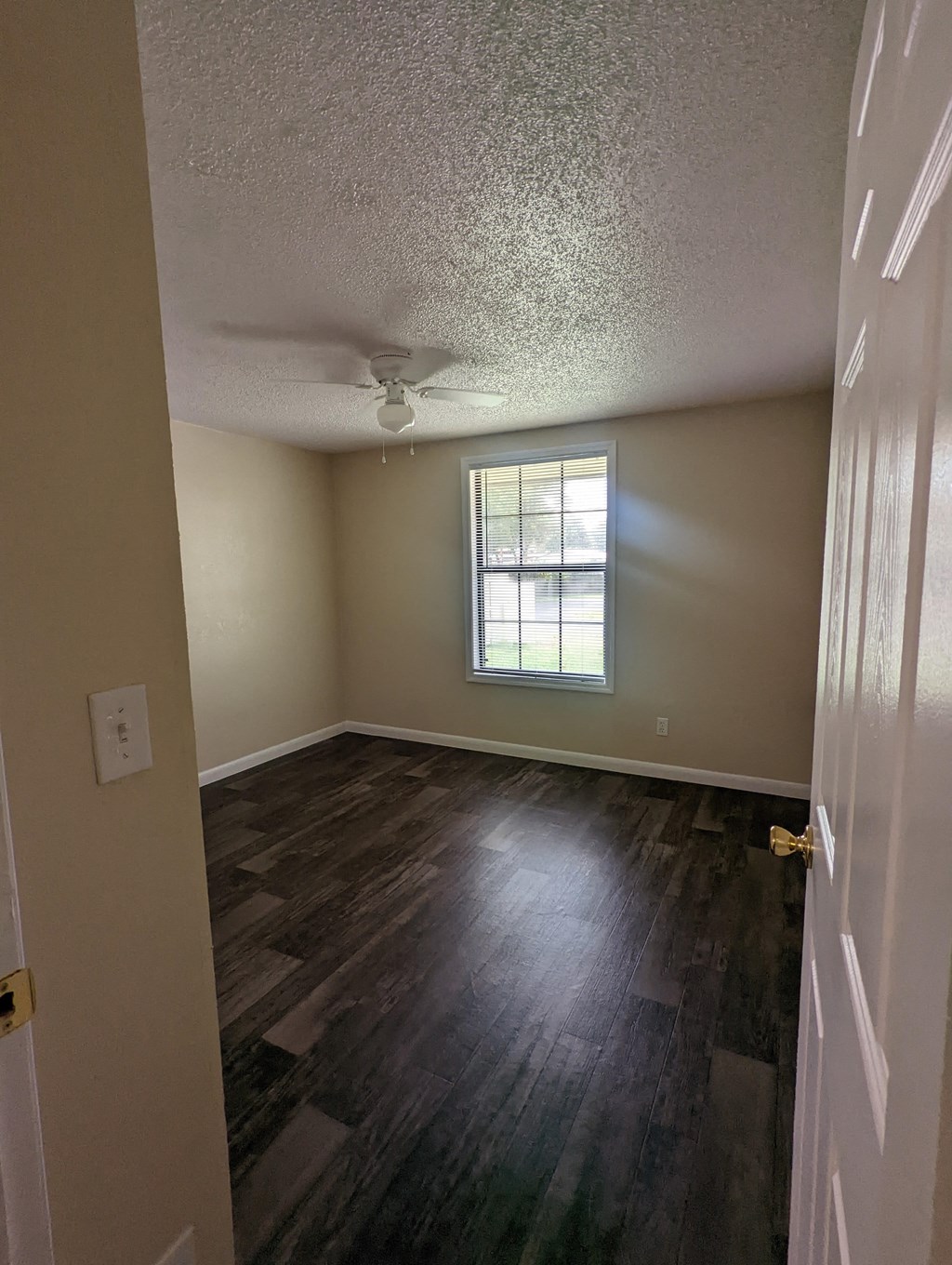 an empty living room with wood floors and a window