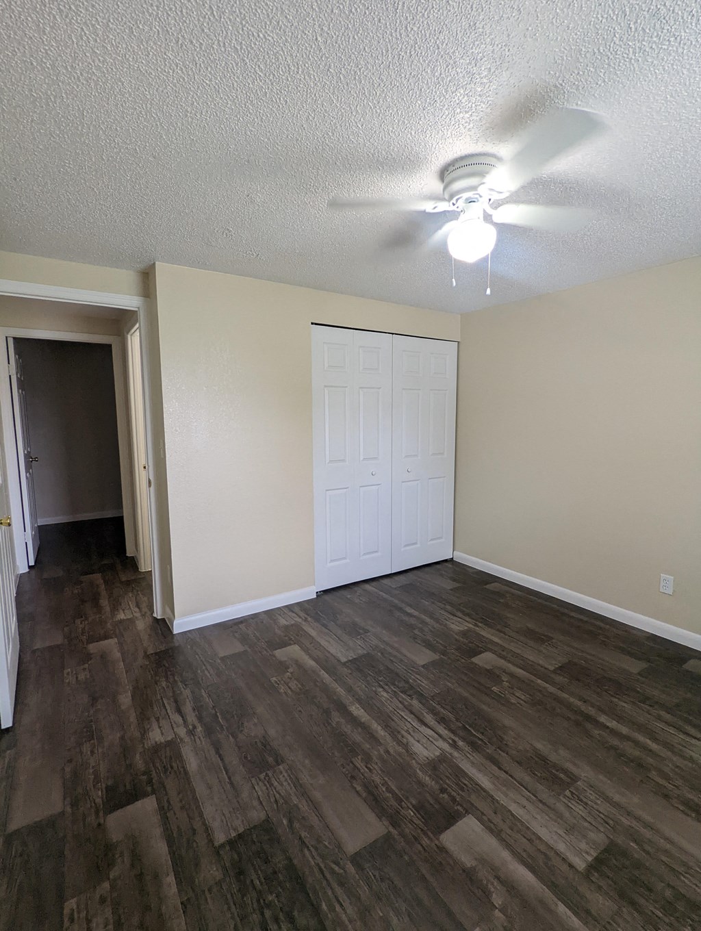 an empty living room with wood flooring and a ceiling fan