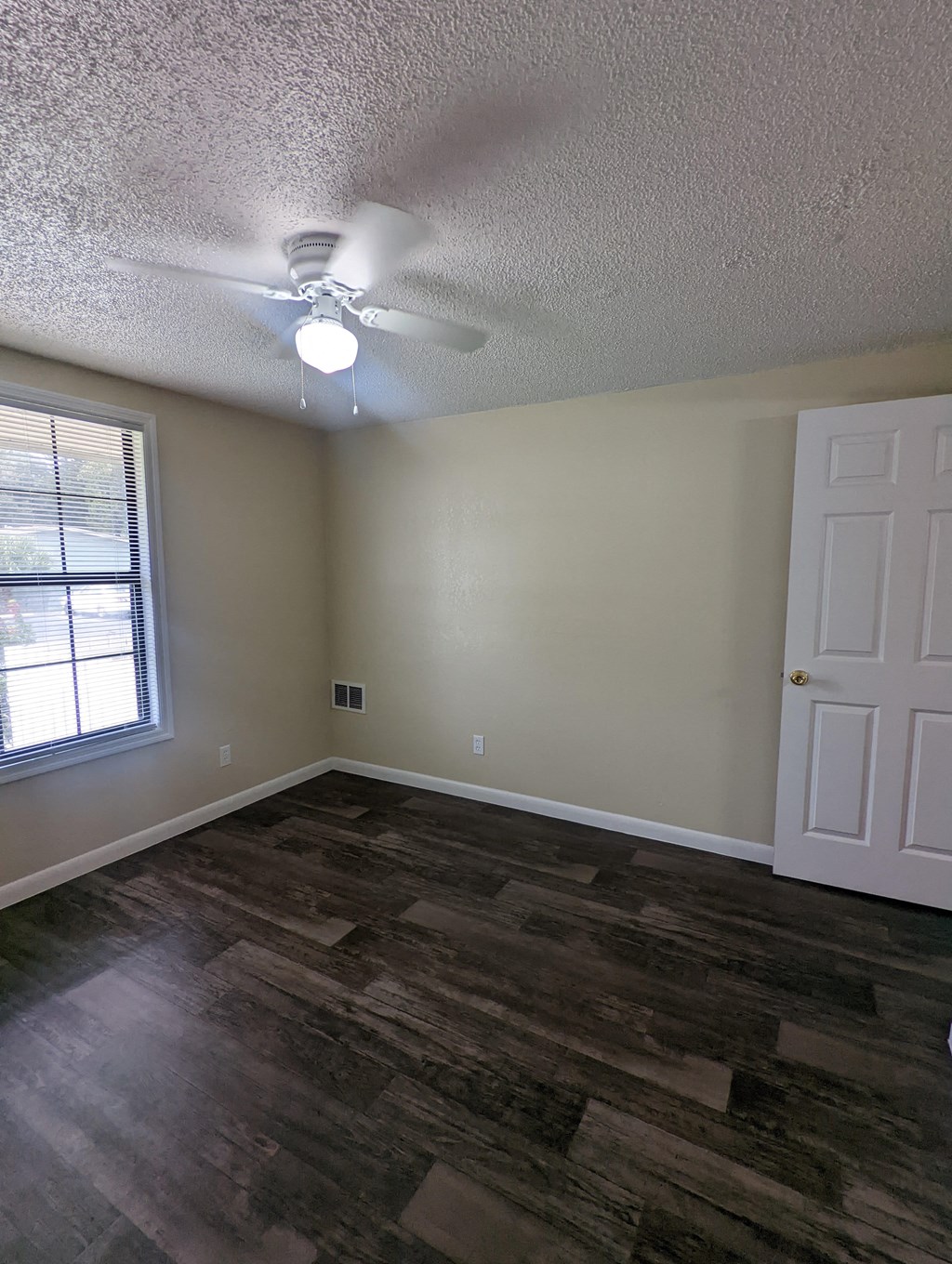 an empty living room with a ceiling fan and a window