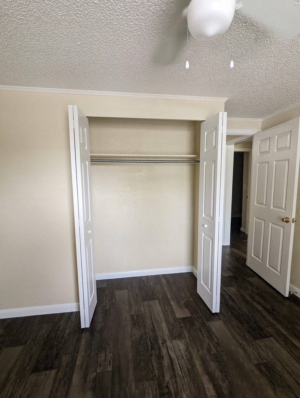 an empty bedroom with a closet and a hallway with a door open