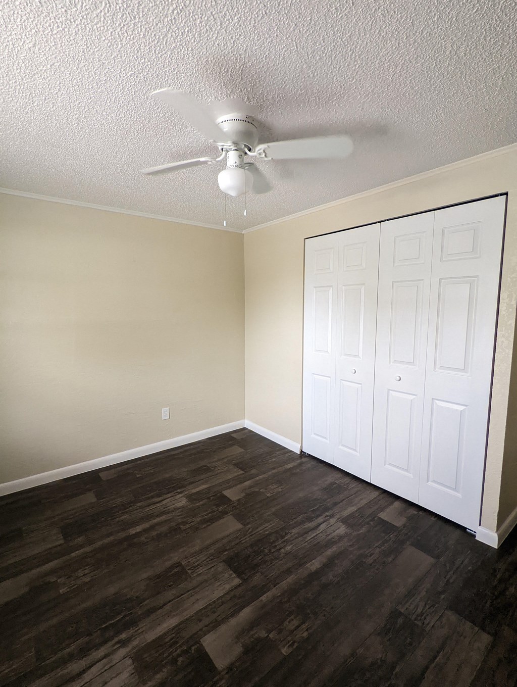 an empty bedroom with a ceiling fan and a closet