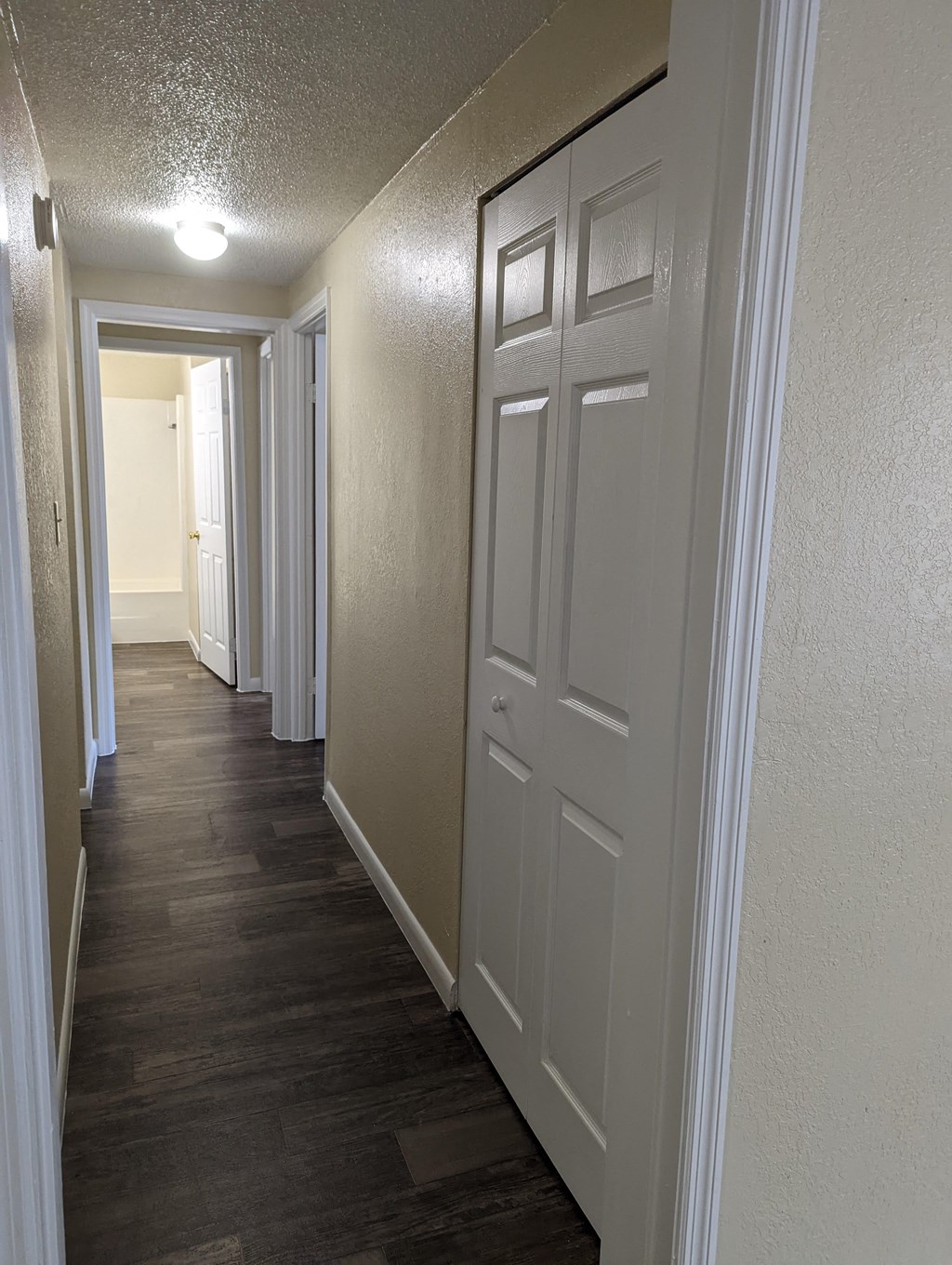 a hallway with white doors and a wood flooring in a home