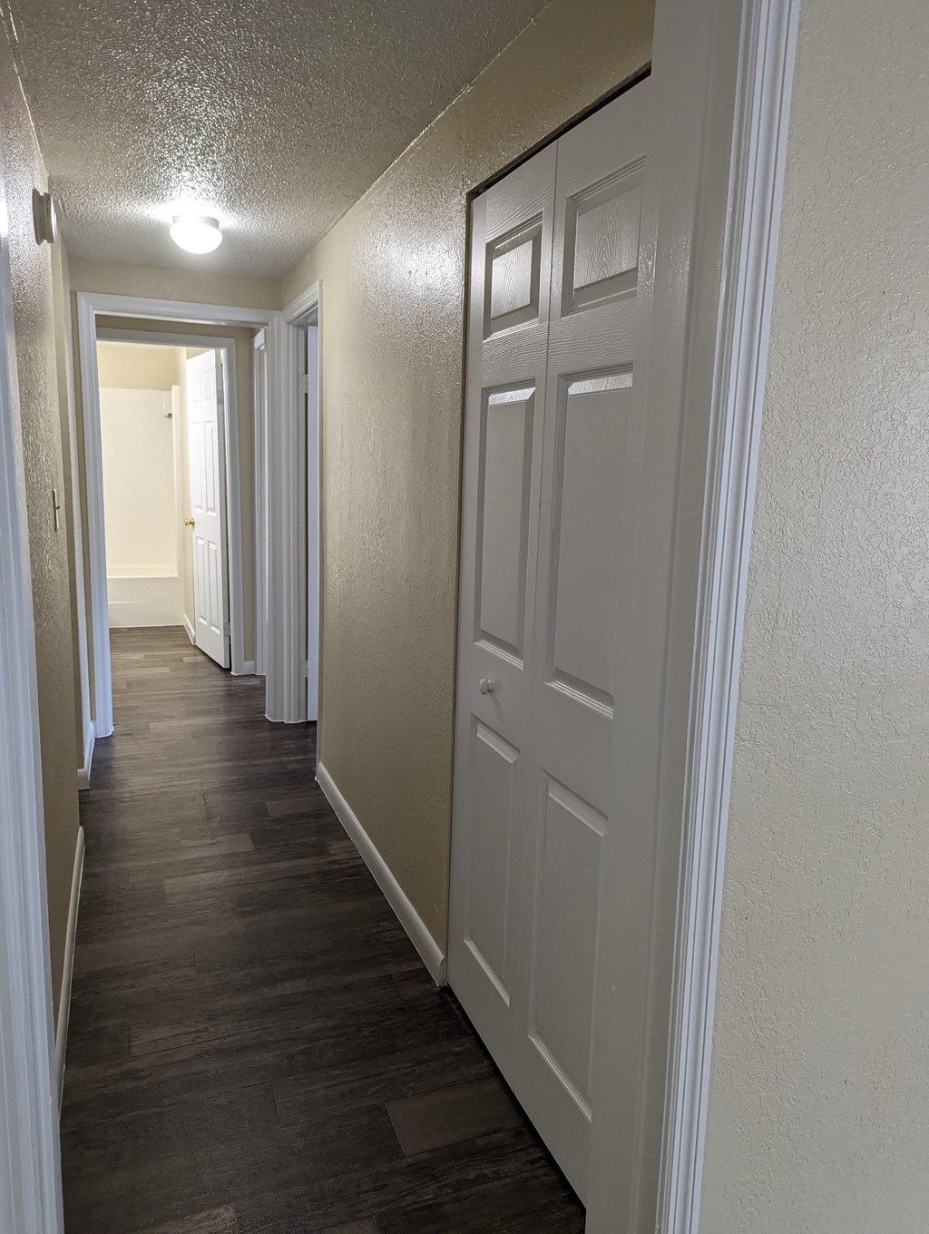 a hallway with white doors and a wood flooring in a home