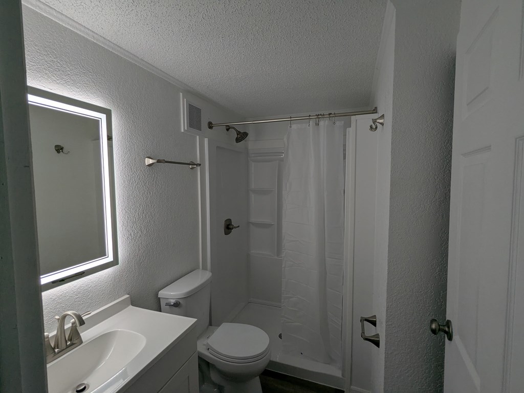 A white bathroom with a toilet, sink, and shower.