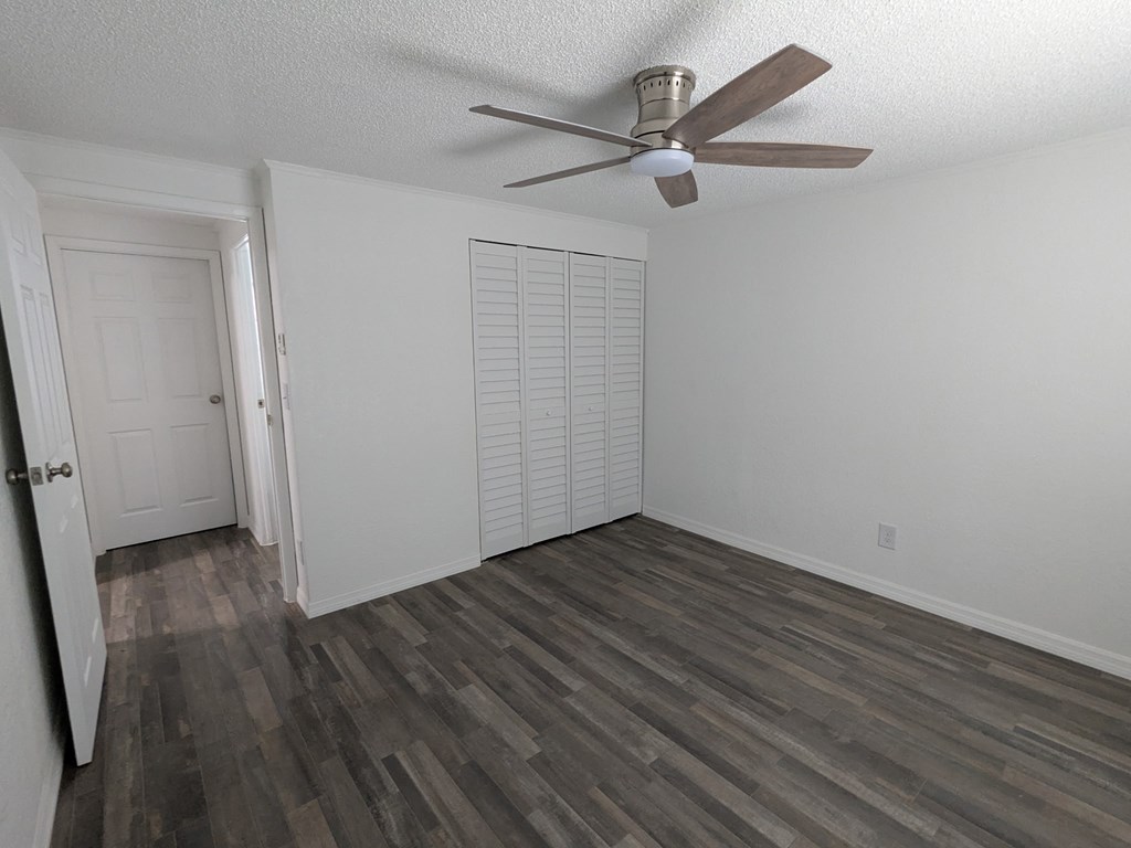 A room with a ceiling fan and wood flooring.