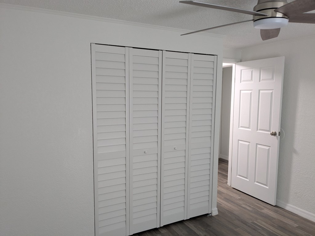 Closet with white doors and a ceiling fan.