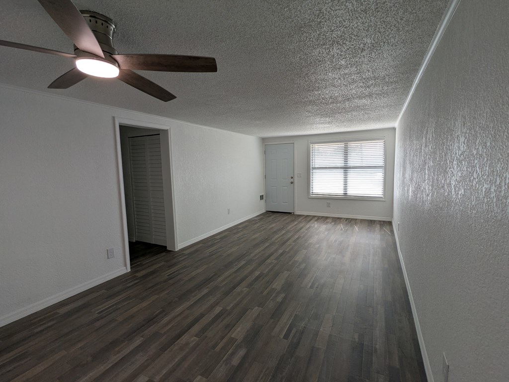 A room with a ceiling fan and wooden flooring.