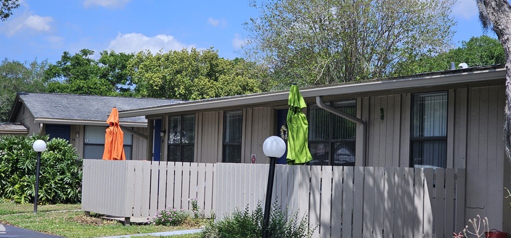 a house with a fence and two umbrellas in front of it