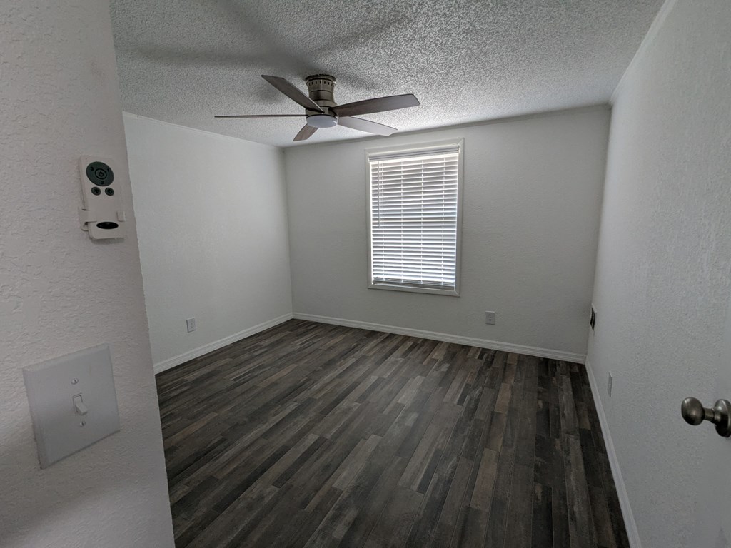 A room with a ceiling fan and wooden flooring.