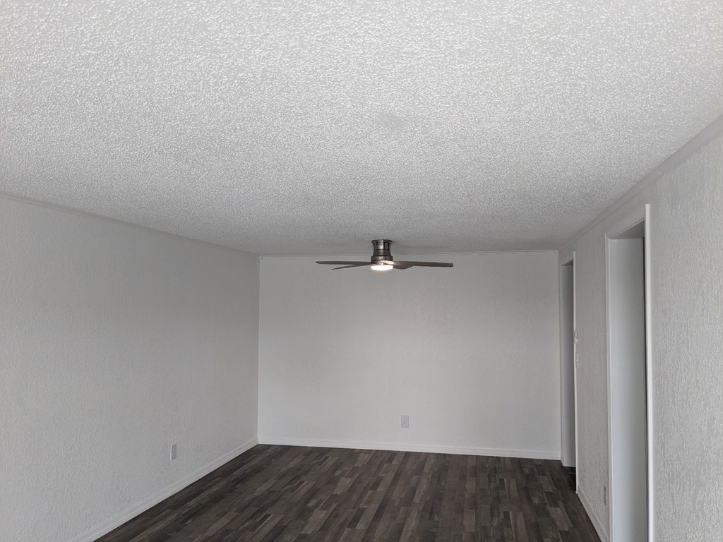 A room with a ceiling fan and wooden flooring.