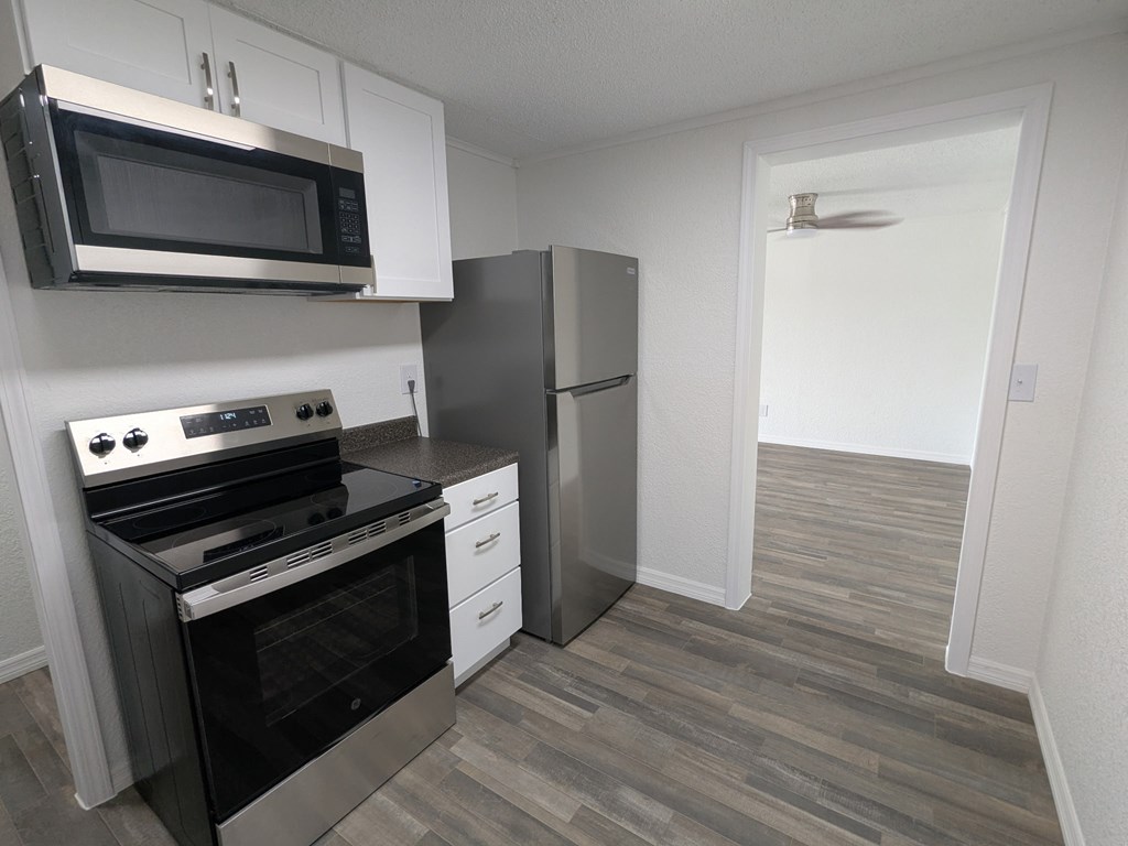A kitchen with a stove, oven, microwave, and refrigerator.
