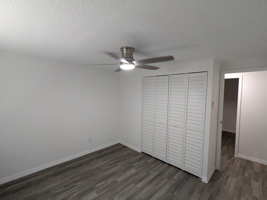 A room with a ceiling fan and a white closet.