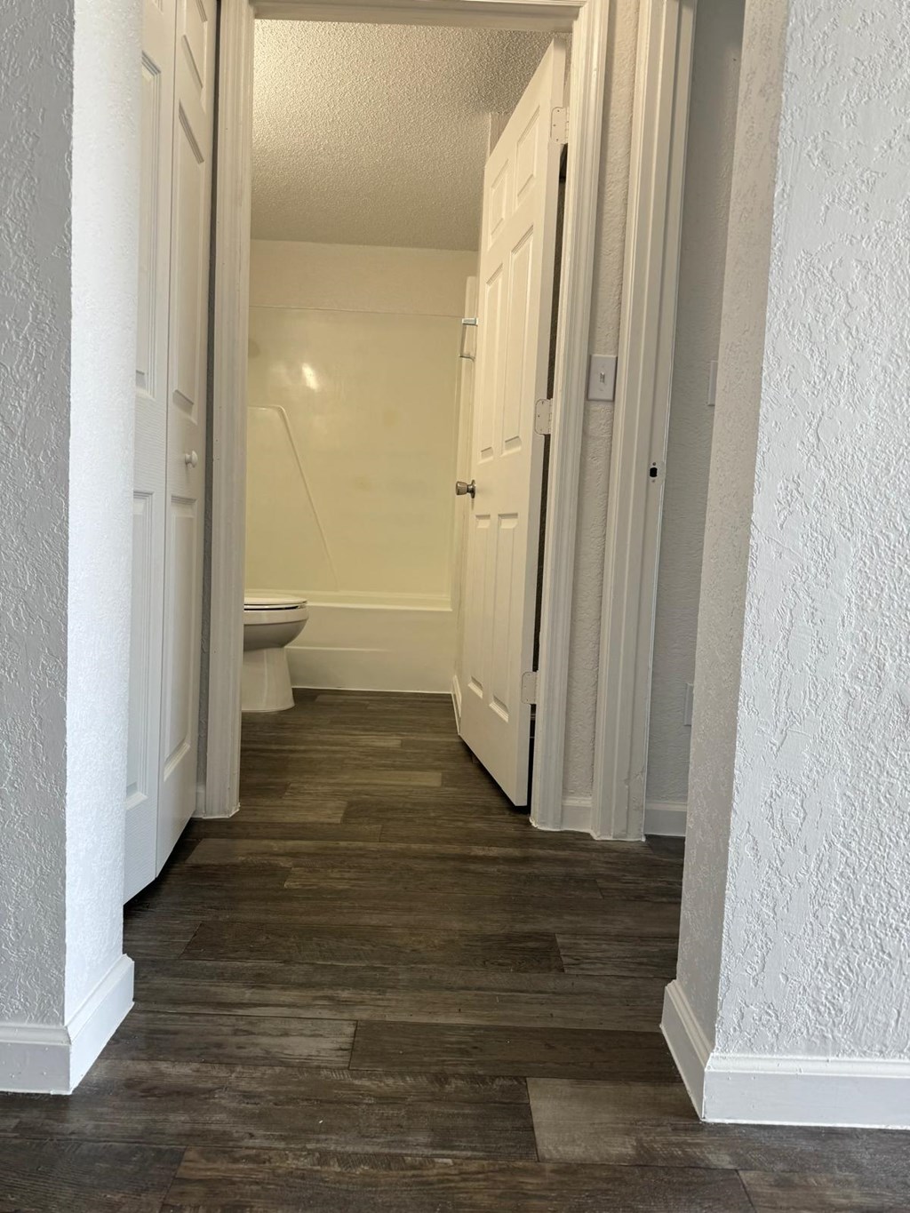 a bathroom with a toilet and a hallway with white doors