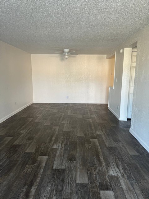 an empty living room with wood floors and a ceiling fan