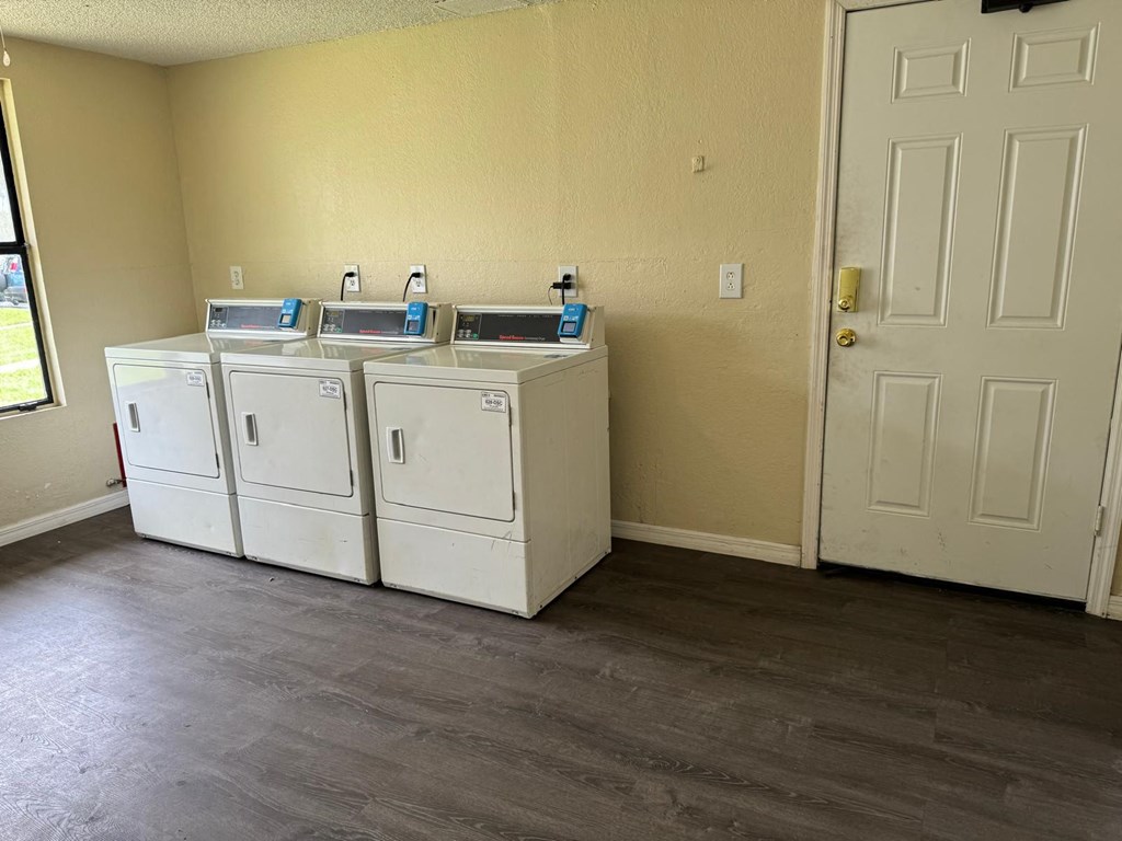 a room with two washers and dryers in it and a door