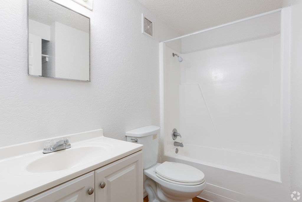A white bathroom with a toilet, sink, and mirror.