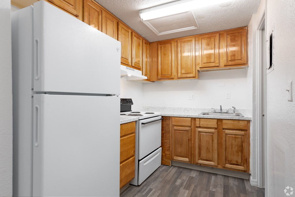 A white refrigerator is in a kitchen with wooden cabinets.