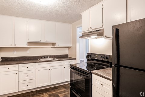 A kitchen with black appliances and white cabinets.