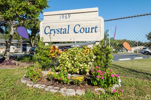 A sign that says Crystal Court in front of a fence.