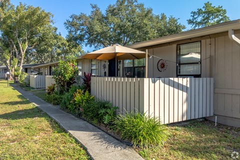 A house with a white fence and a brown umbrella.