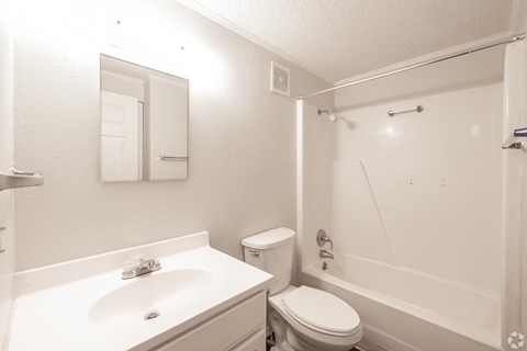 A white bathroom with a sink, toilet, and bathtub.