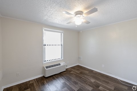 A room with a ceiling fan and a window with blinds.