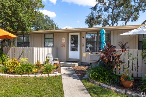 A small house with a white picket fence and a garden in front.