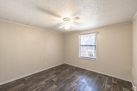 A room with a ceiling fan and a window with blinds.