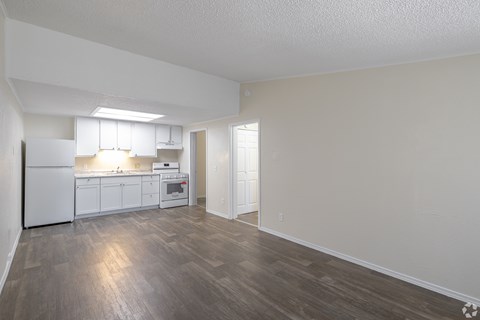A kitchen with white appliances and wooden floors.