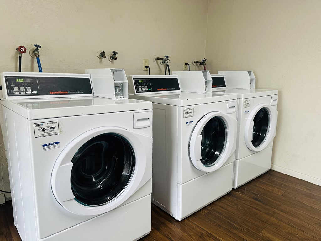 a group of washing machines and dryers in a laundry room