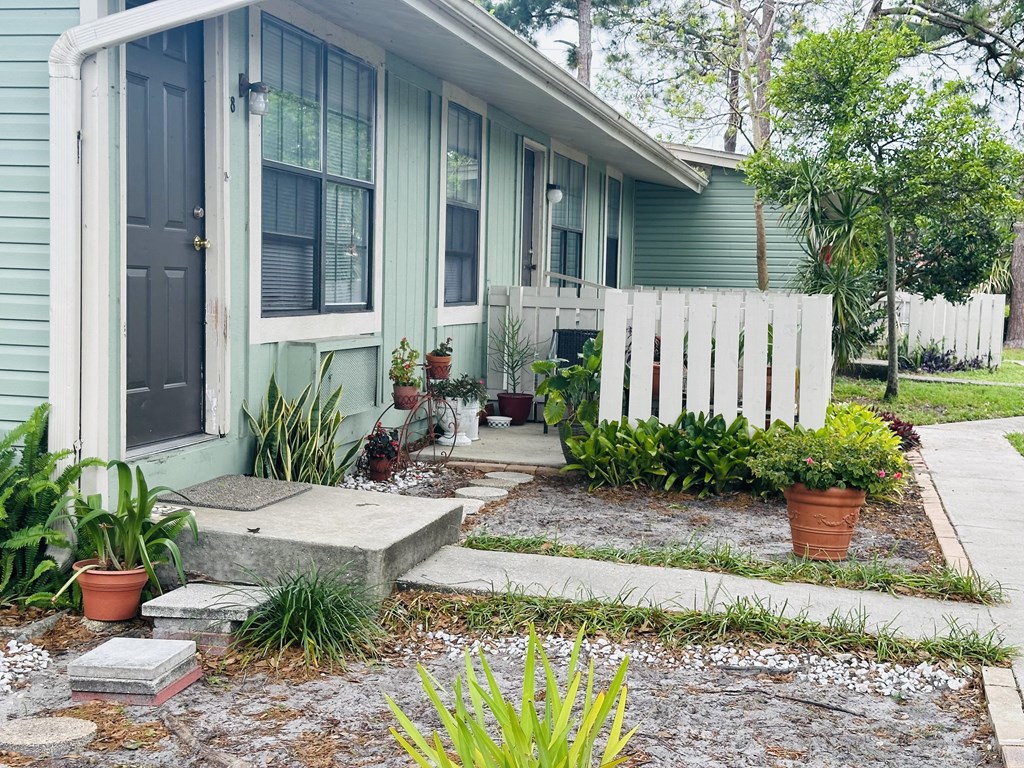 a blue house with a white fence and plants in front of it