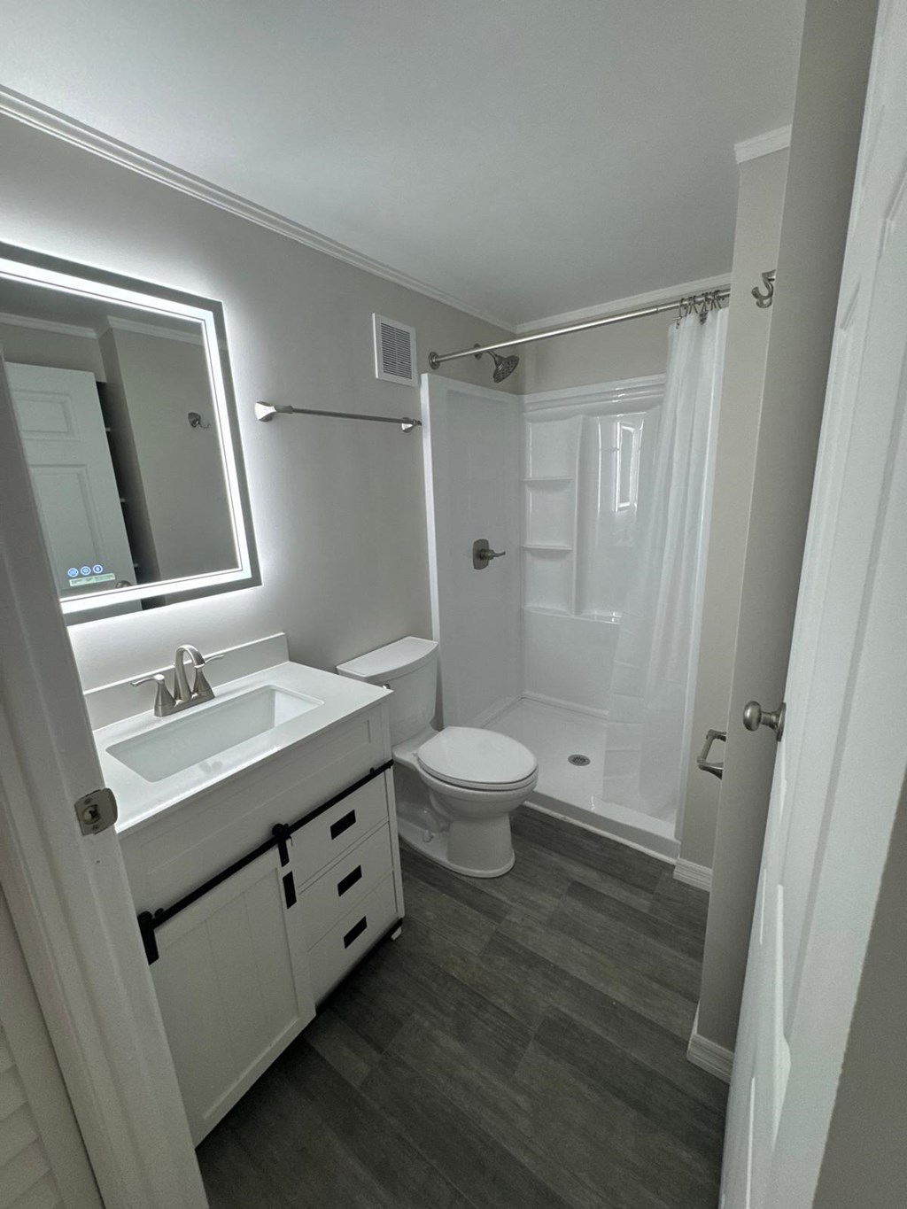 A white bathroom with a toilet, sink, and shower.