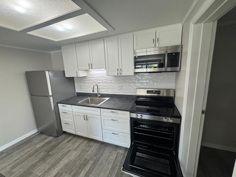 A kitchen with white cabinets and a black stove top oven.