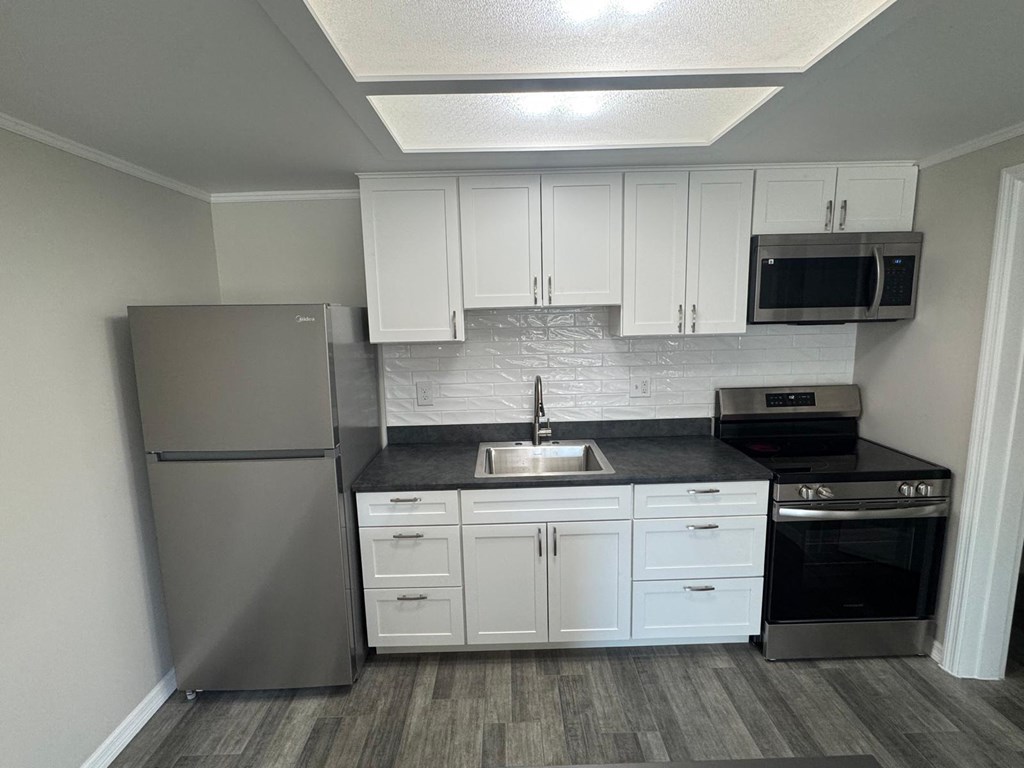A kitchen with a refrigerator, sink, and oven.