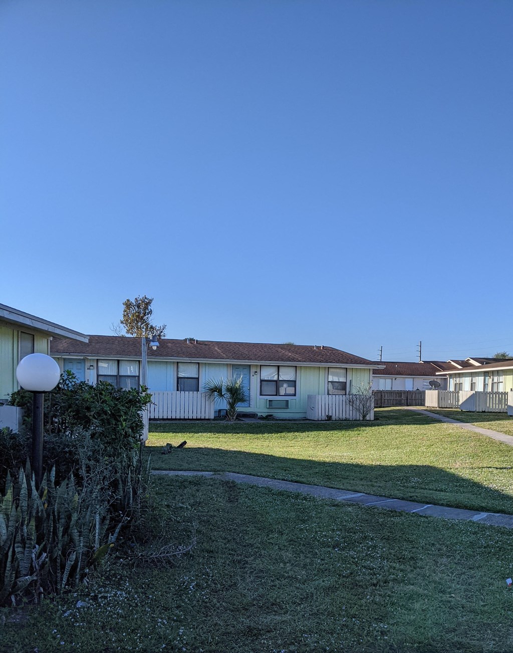 a row of houses with a yard and a blue sky
