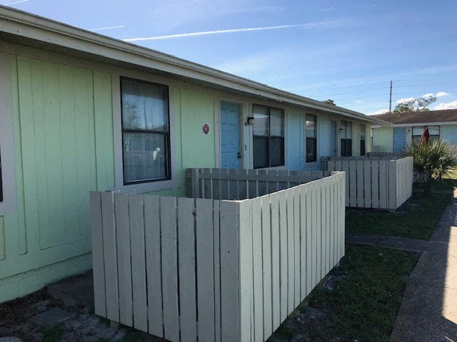 a green house with a white fence in front of it