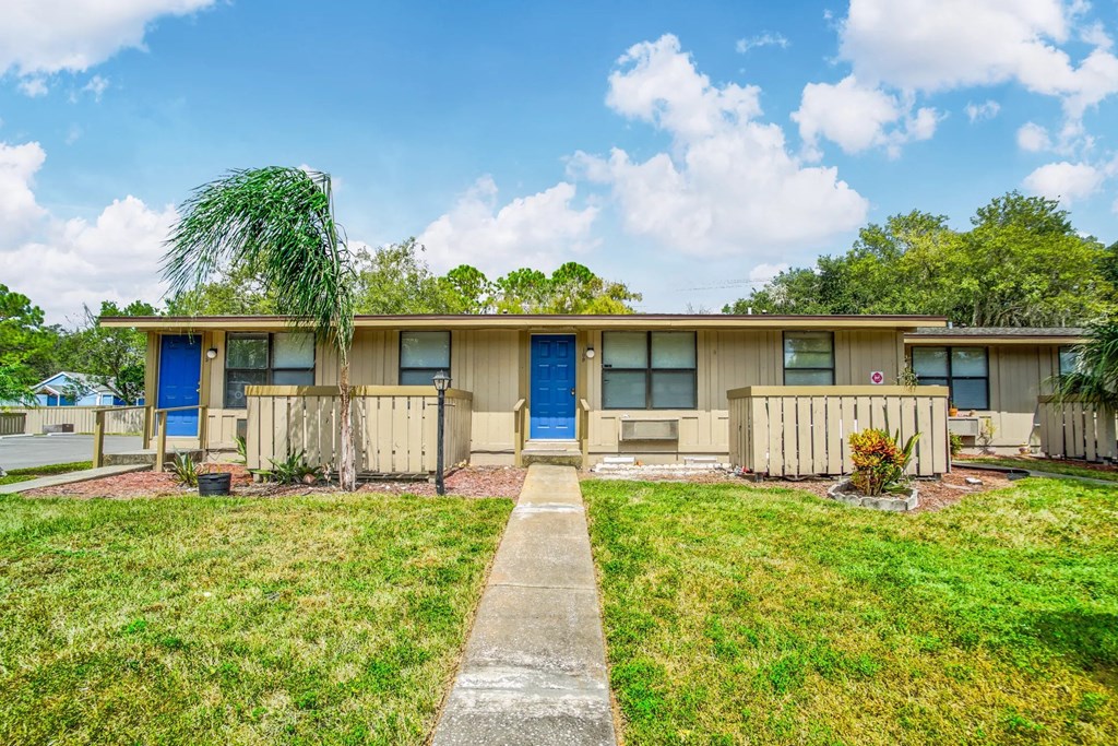 a home with blue doors and a lawn and a pathway
