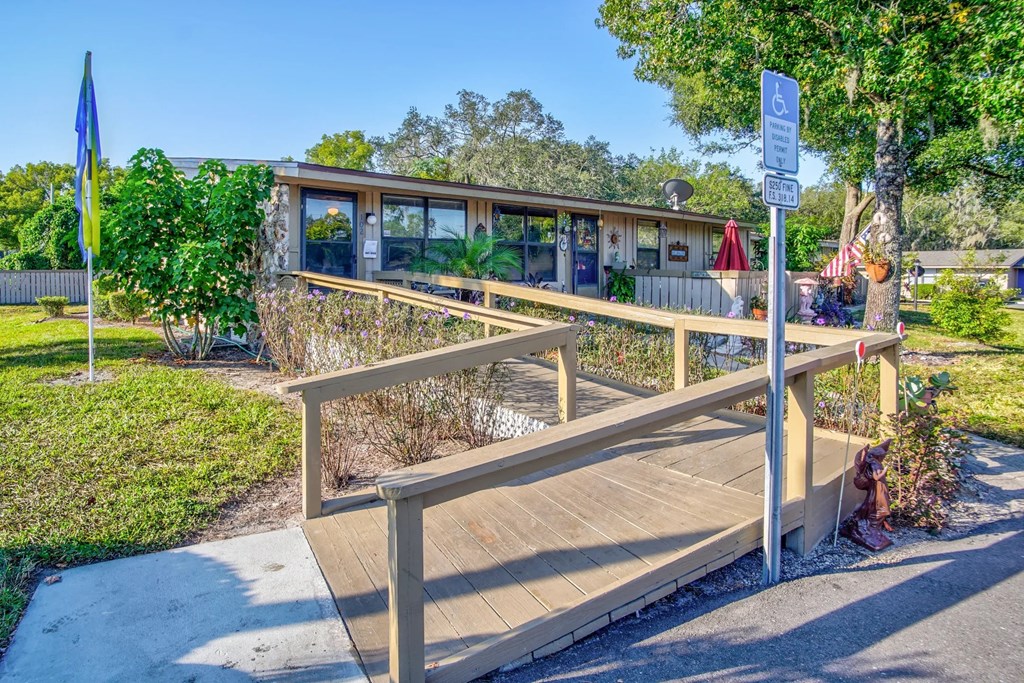 a wooden bridge in front of a building with trees and a sidewalk