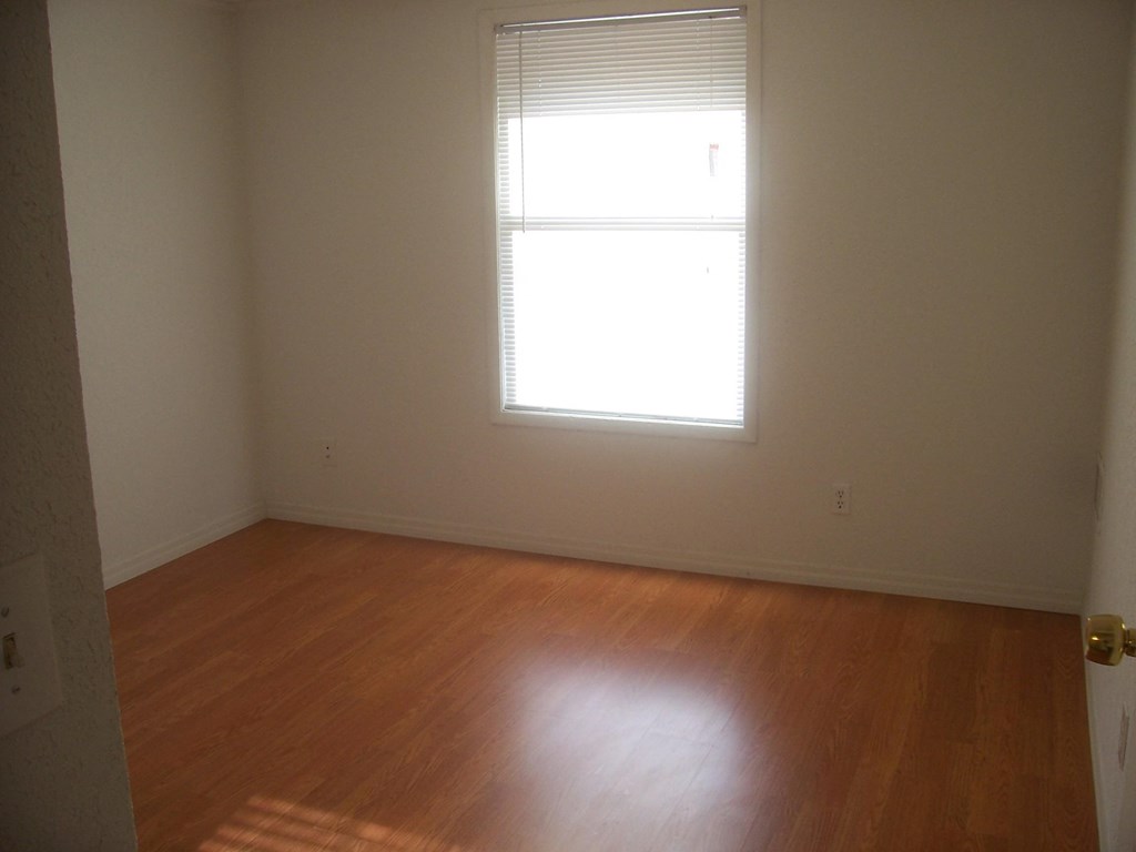 an empty room with wooden floors and a window