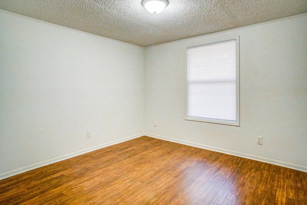 an empty room with wood floors and a window