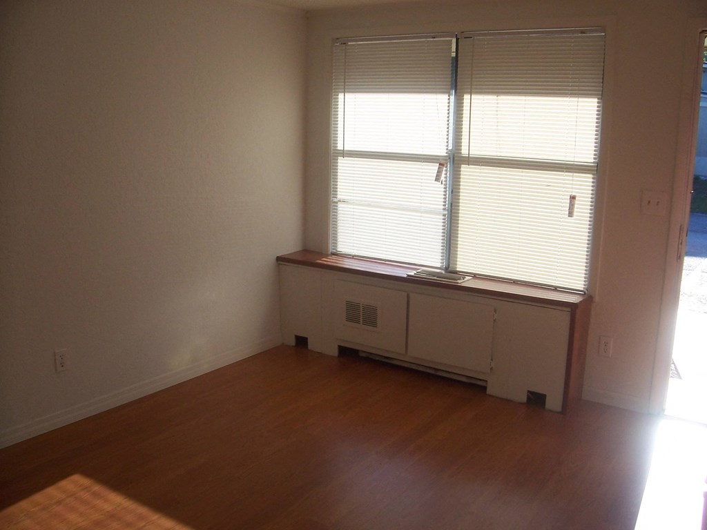 an empty room with a window and a wooden floor