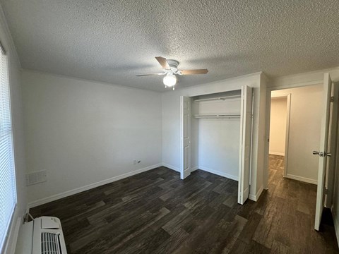 an empty living room with a ceiling fan and a closet