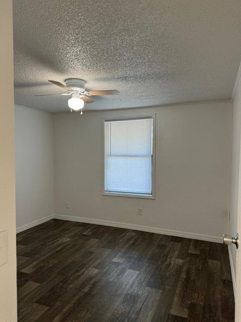 an empty room with a ceiling fan and a window