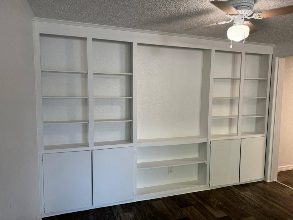 a room with white shelves and a ceiling fan