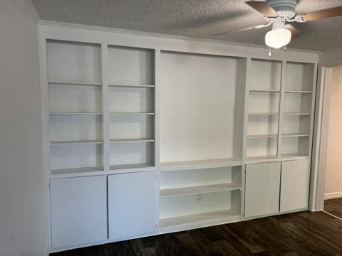 a room with white shelves and a ceiling fan