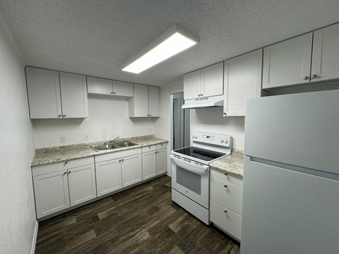 an empty kitchen with white cabinets and white appliances