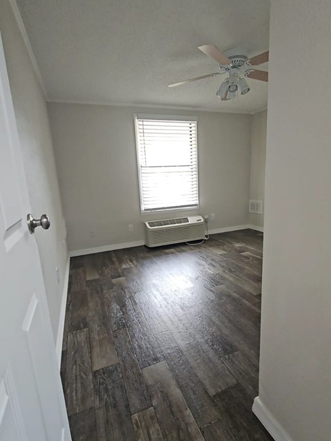 A room with a ceiling fan and a window with blinds.
